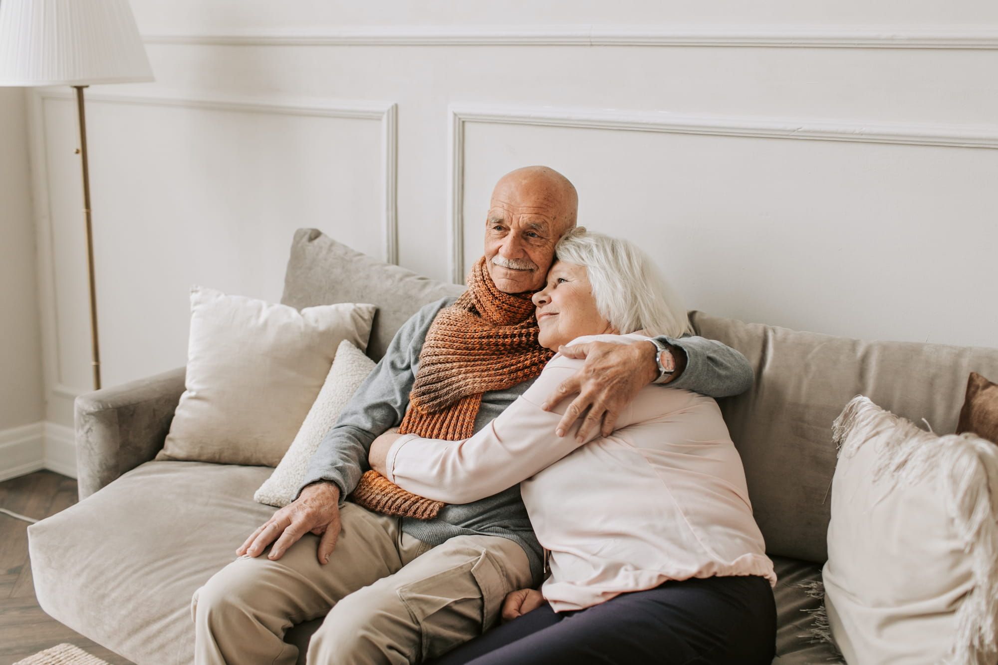 Glückliches Rentnerpaar sitzt auf einem hellen Sofa und umarmt sich